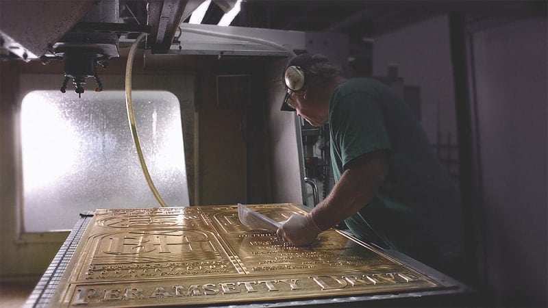 worker reviewing and manufacturing a large bronze plaque in the signage factory