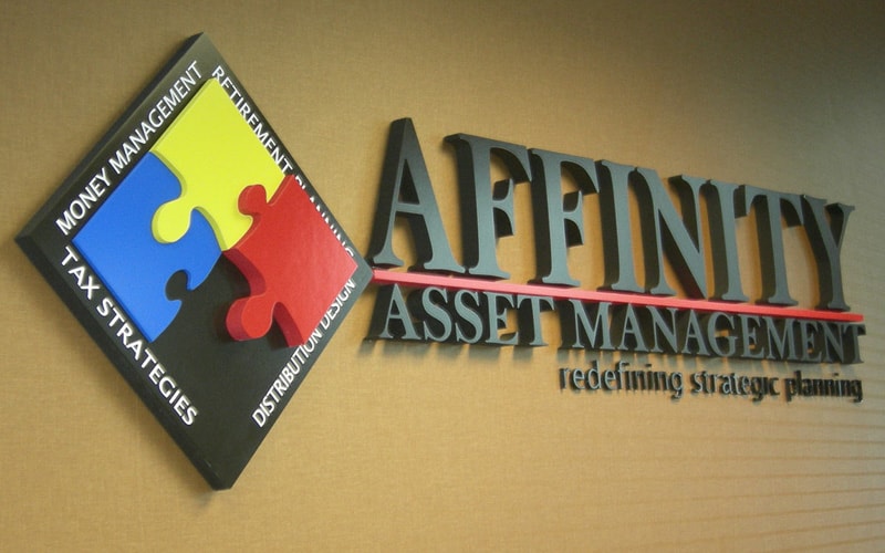 Custom foam indoor sign with black letters and puzzle piece logo on brown wall