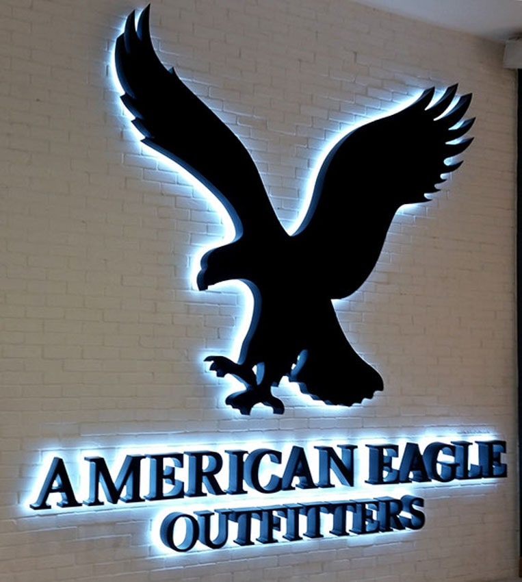 Custom backlit eagle logo sign with black lettering on white brick wall